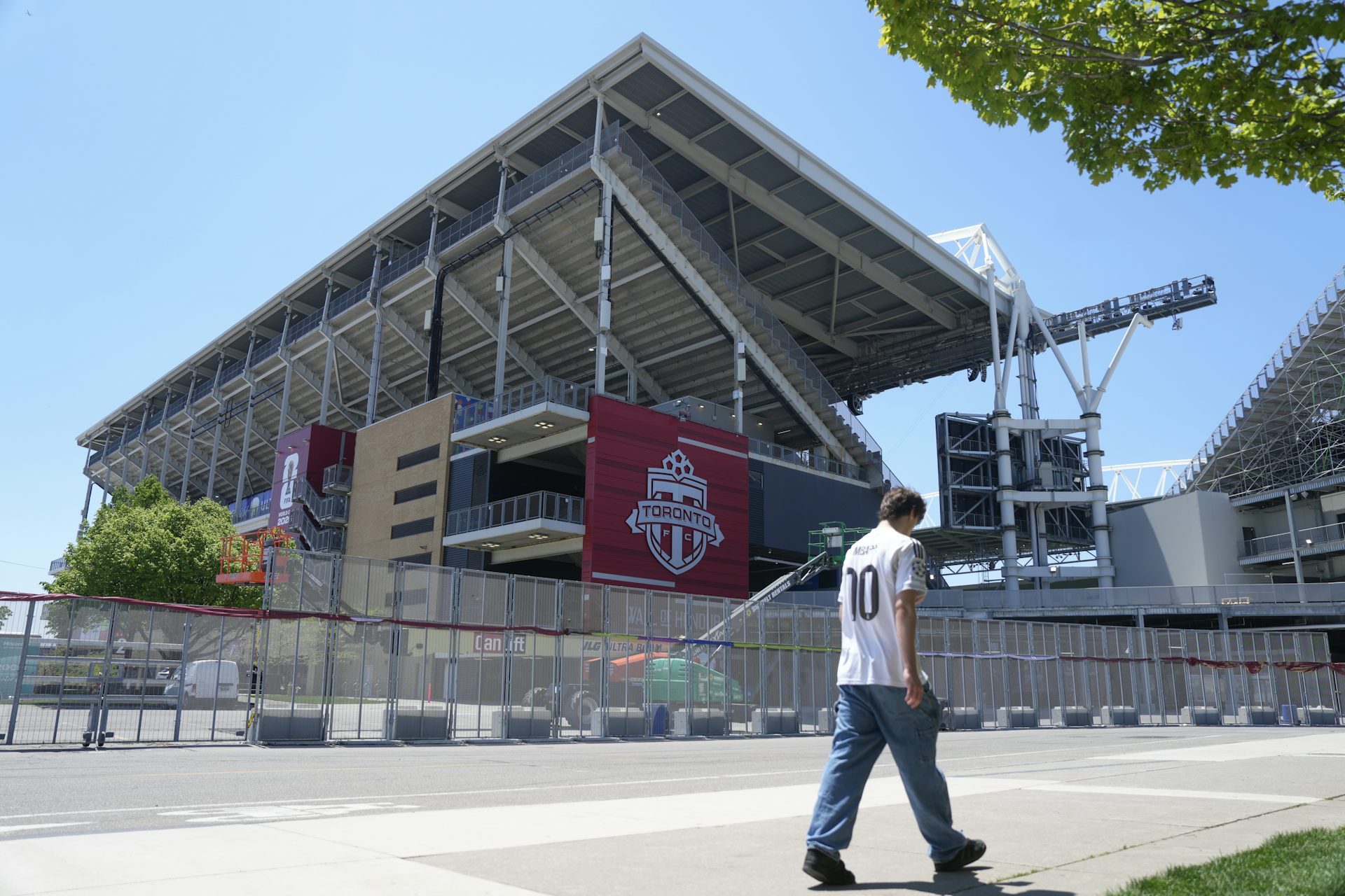 Una persona con jeans y camiseta blanca camina por un estadio al aire libre