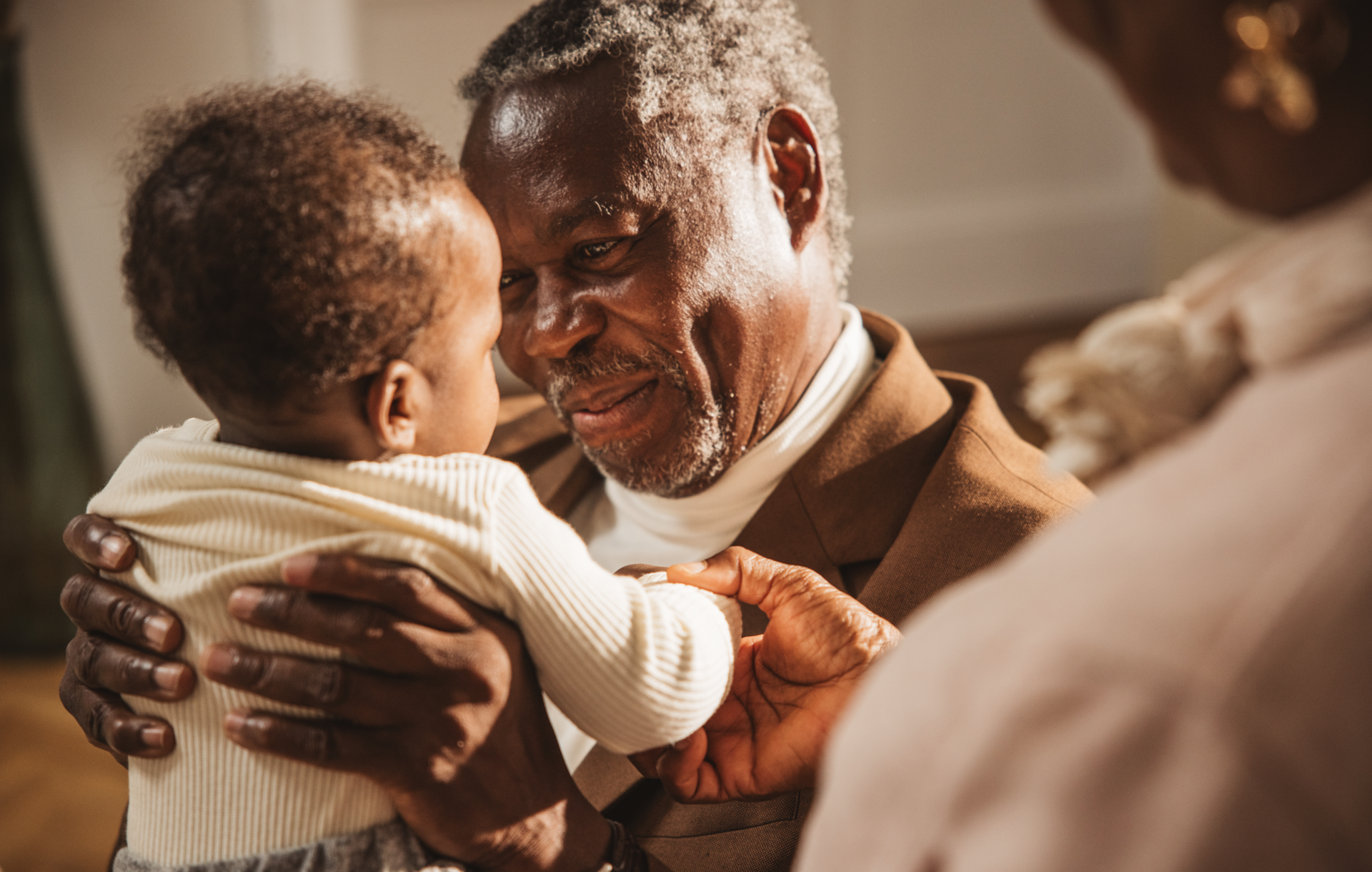 An older man holds and smiles at a baby.