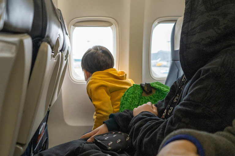 A small child looks out of the window of a plane.