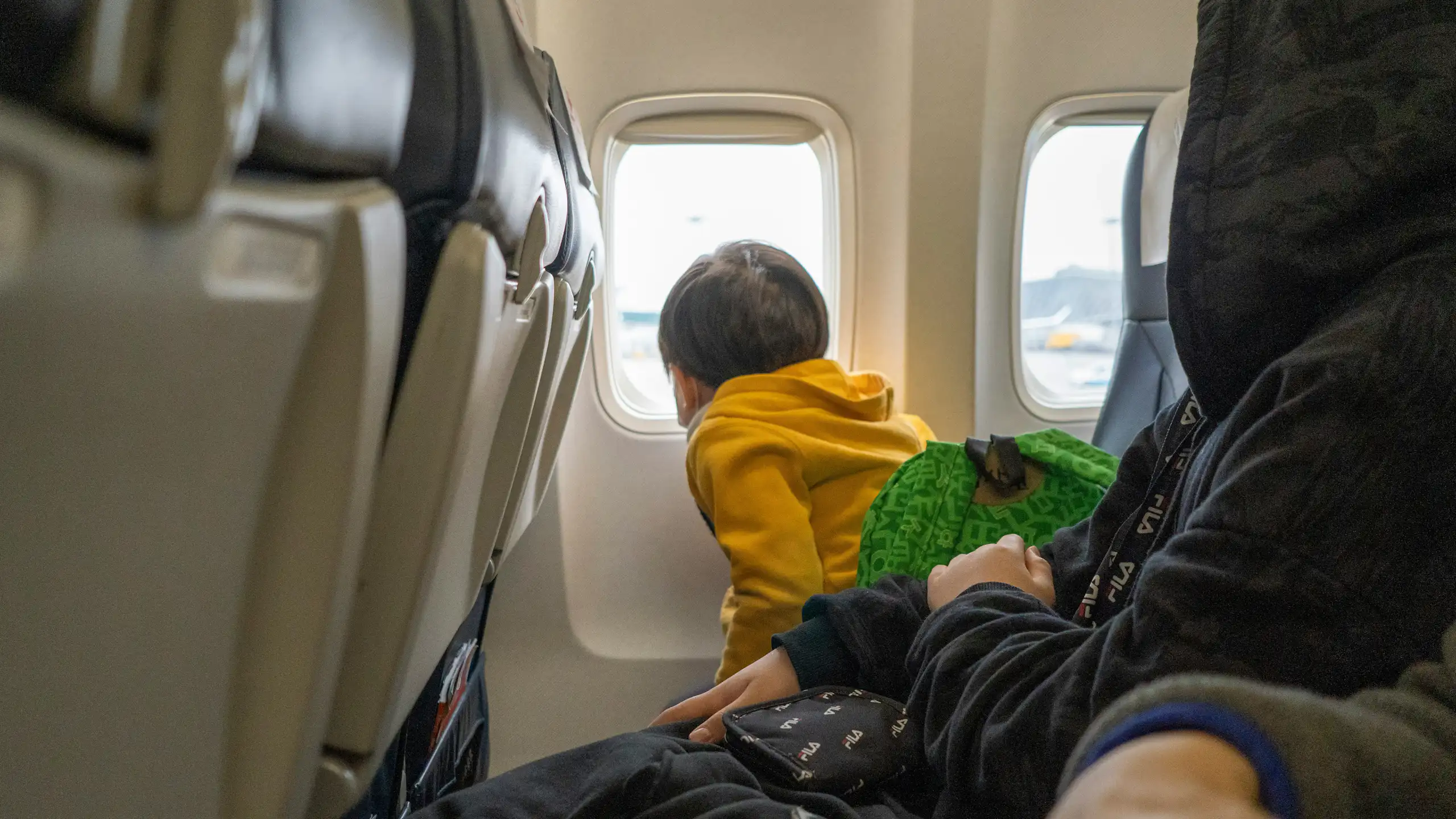 A small child looks out of the window of a plane.