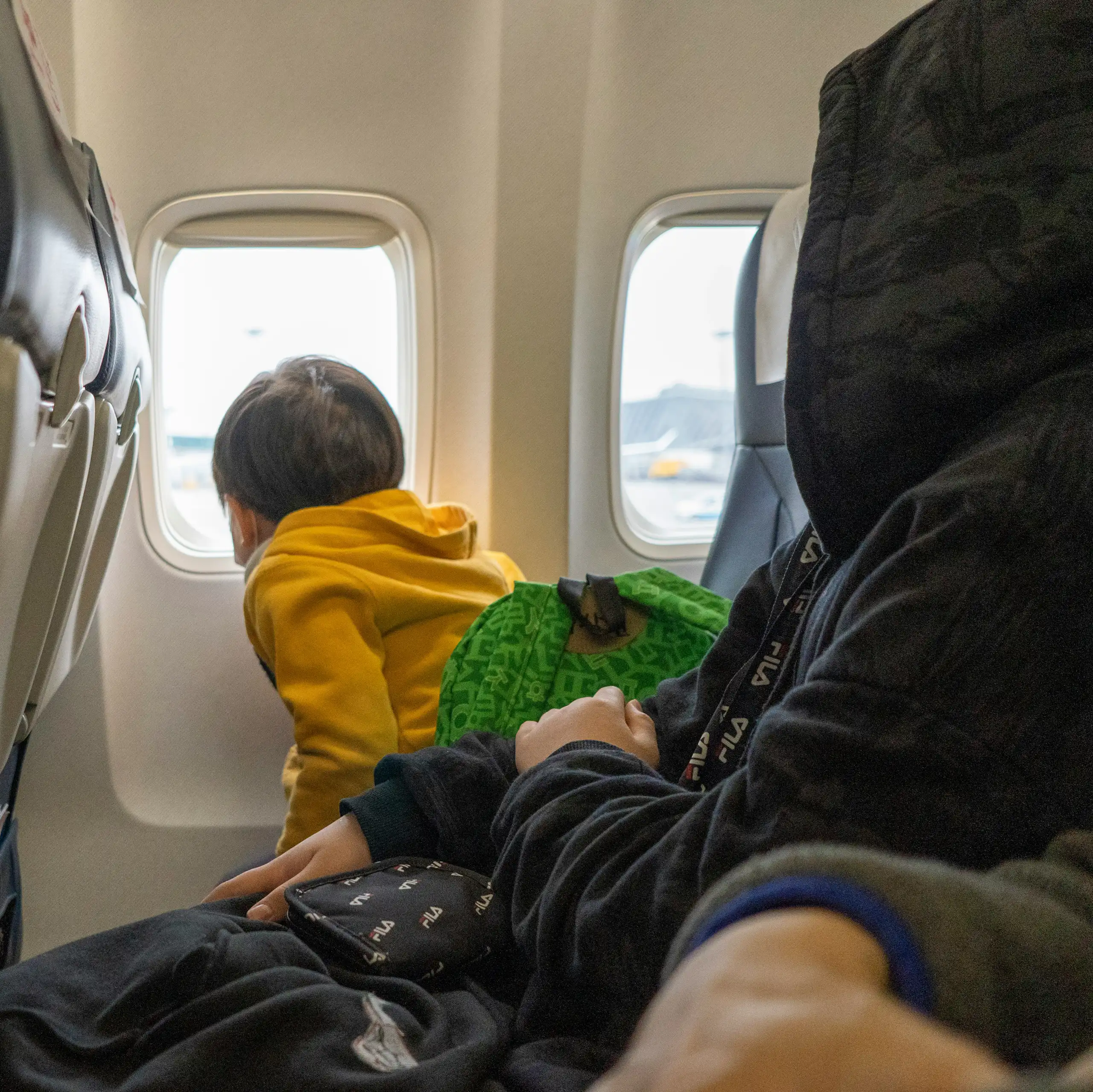 A small child looks out of the window of a plane.