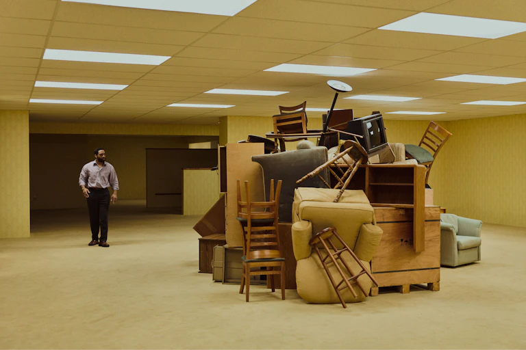 Chiwetel Ejiofor stood in a yellow room looking at a large pile of furniture