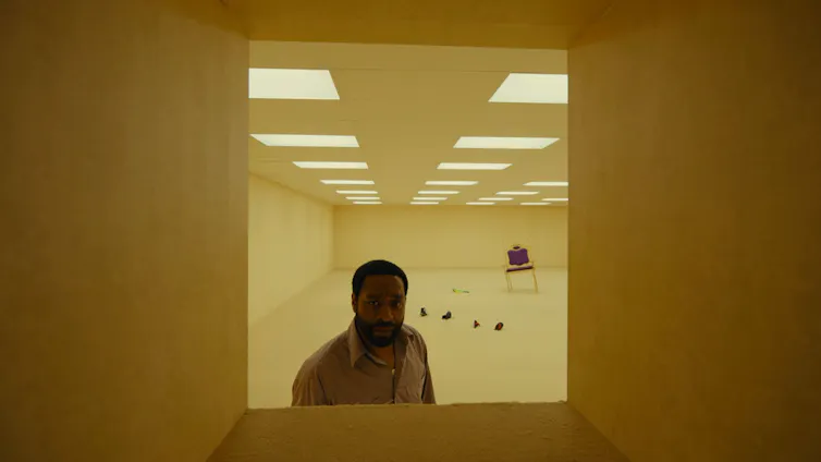 Chiwetel Ejiofor in an endless loop of yellow corridors.