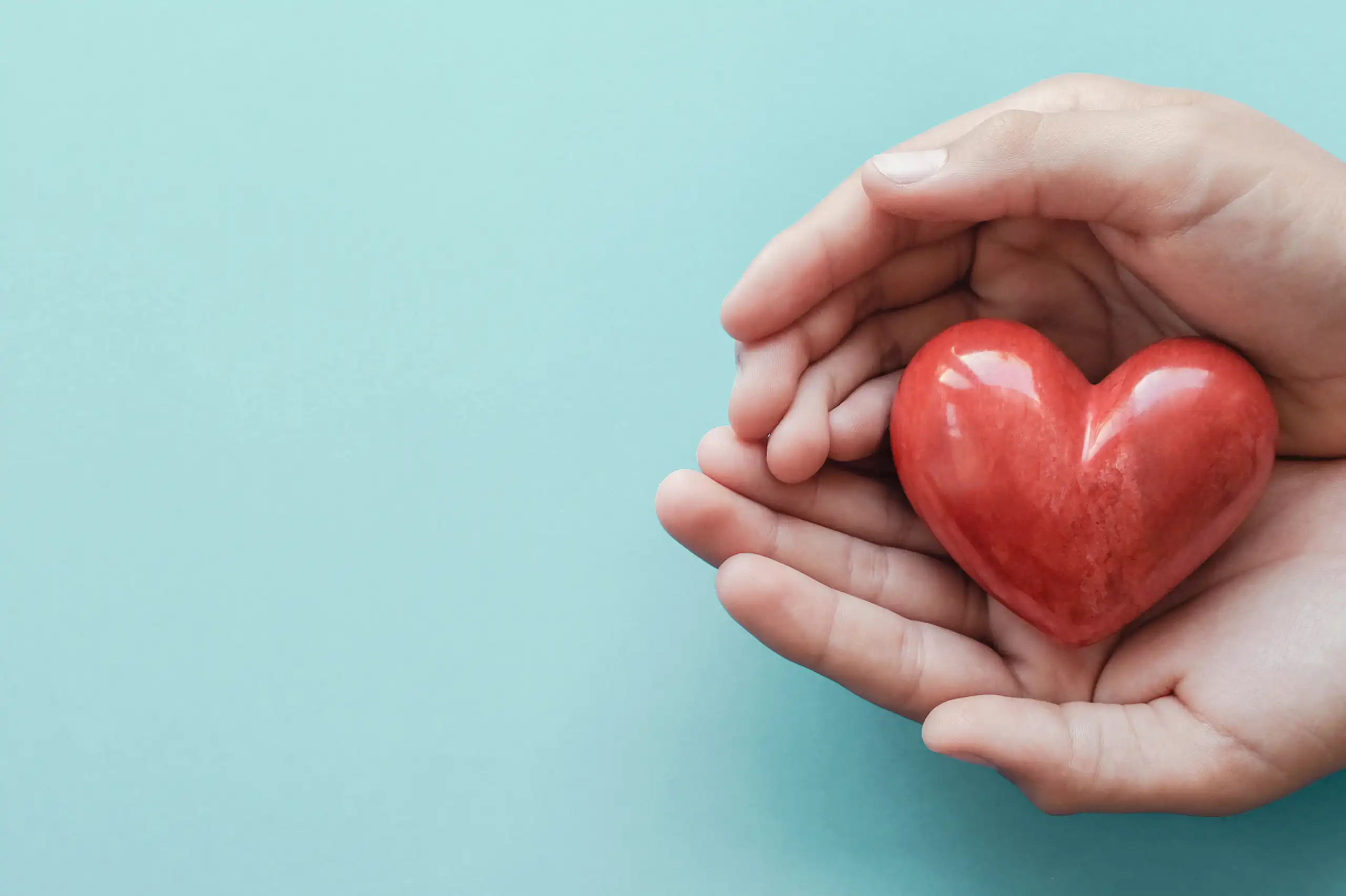 Une main entoure un coeur rouge.