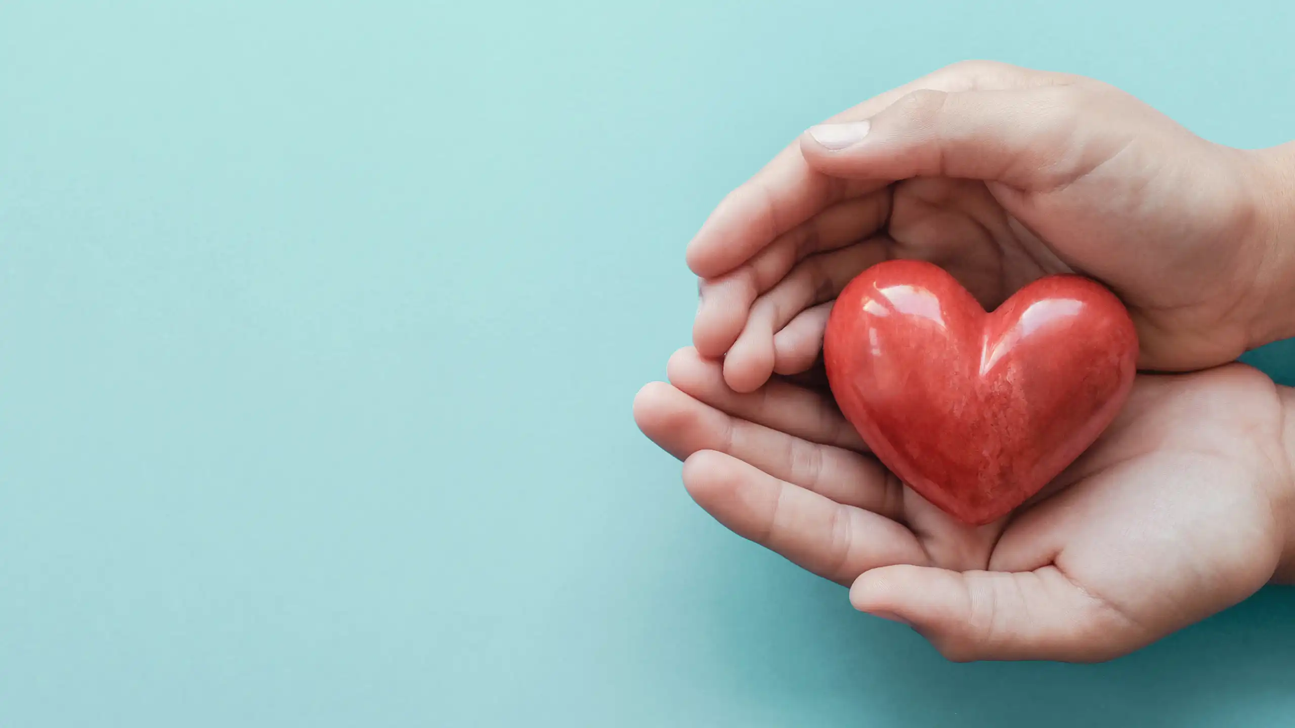 Une main entoure un coeur rouge.