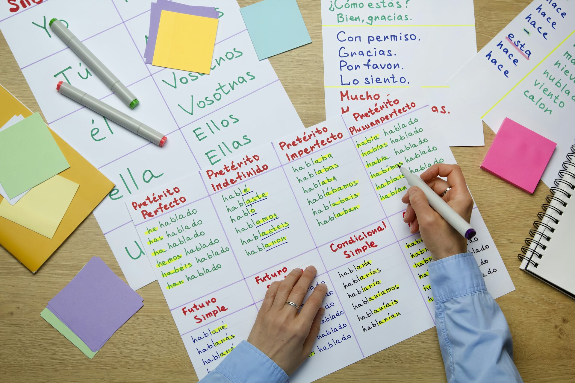 Vista cenital de unas manos infantiles escribiendo y hojas de ejercicios de escritura desperdigadas