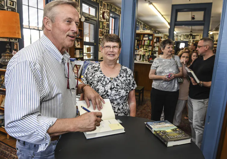 a man signing a book for a woman