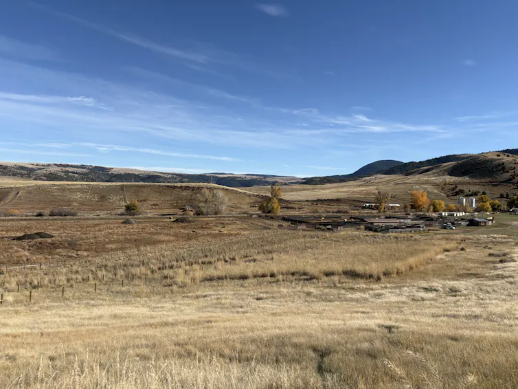 A wide view of a grassy, hilly area with various barns and other buildings visible.