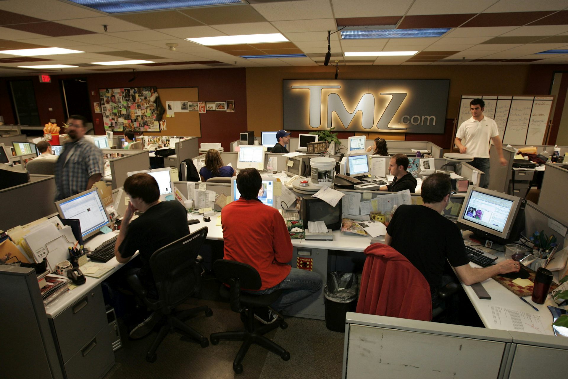A crowded newsroom with cubicles and desktop computers.
