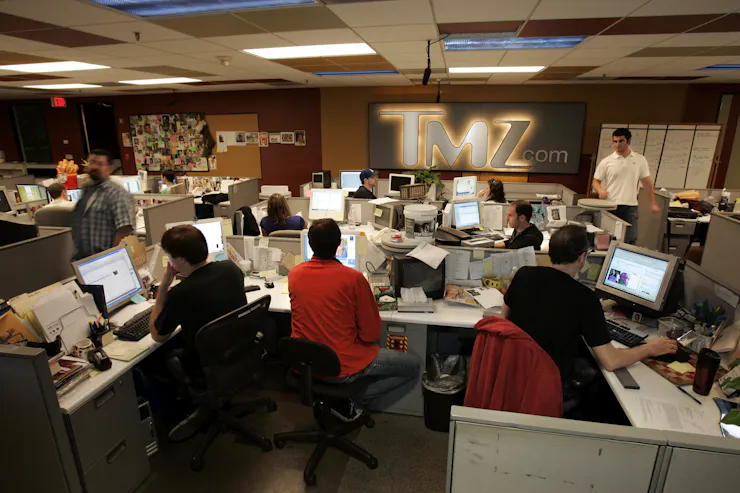 A crowded newsroom with cubicles and desktop computers.