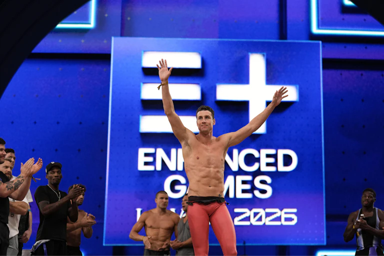 A swimmer in a competition holds his arms aloft in victory.