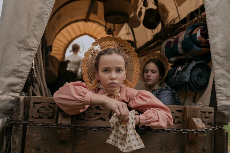 A young girl in the back of a wagon.