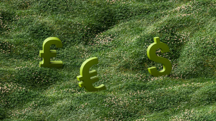 Pound, euro and dollar signs sitting on a grassy hill