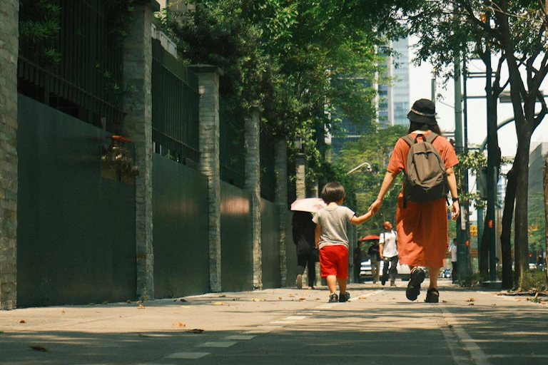 A parent walks with a child on a city street.