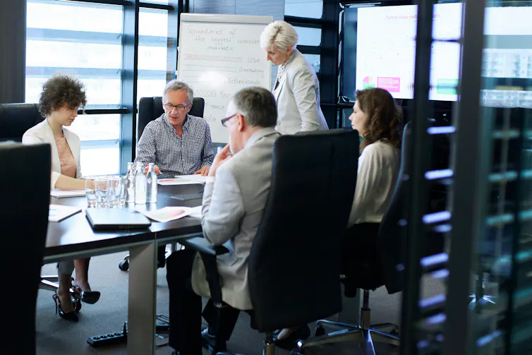 Los esfuerzos para estandarizar las puntuaciones ESG podrían hacer que el lavado verde corporativo sea más fácil, no más difícil 1 Un grupo de personas reunidas alrededor de una mesa de conferencias.