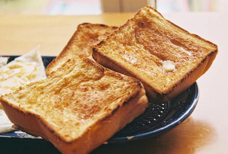 Three pieces of nicely browned toast sit on a plate.