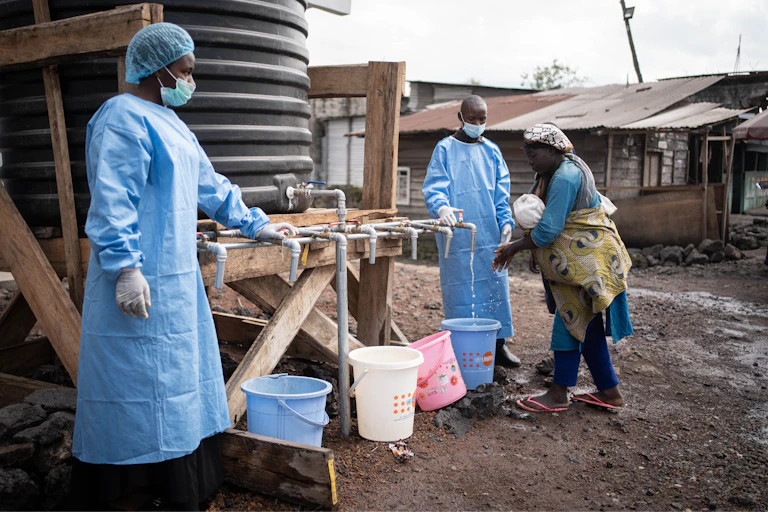 Health workers in protective gowns and masks at a checkpoint set up for preventive measures against Ebola.