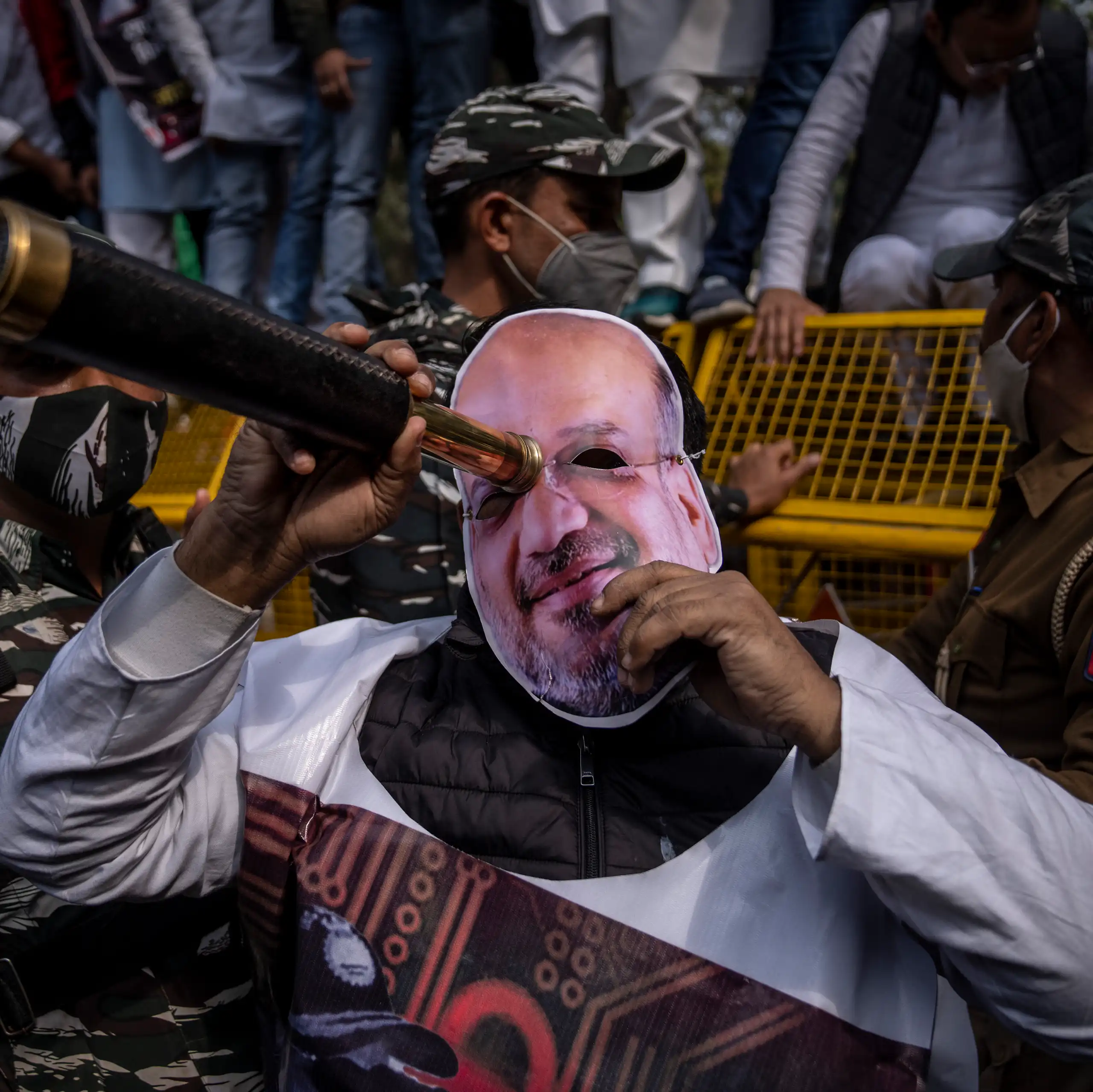 A protester wearing a mask of Amit Shah, India's home minister, looks through a scope during a rally accusing Prime Minister Narendra Modi's government of using military-grade spyware to monitor political opponents, journalists and activists.