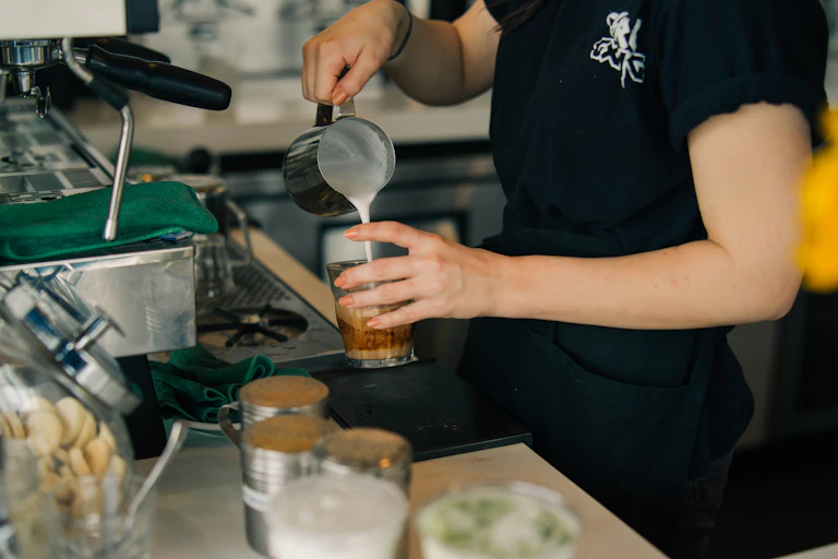 A fbarista pouring a coffee