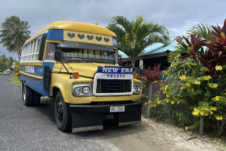 A yellow and blue Samoan-style bus, with a sign saying 'new era' above the number plate.