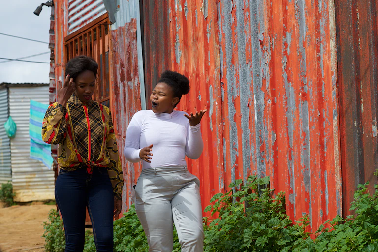 Two young women walking past a shack