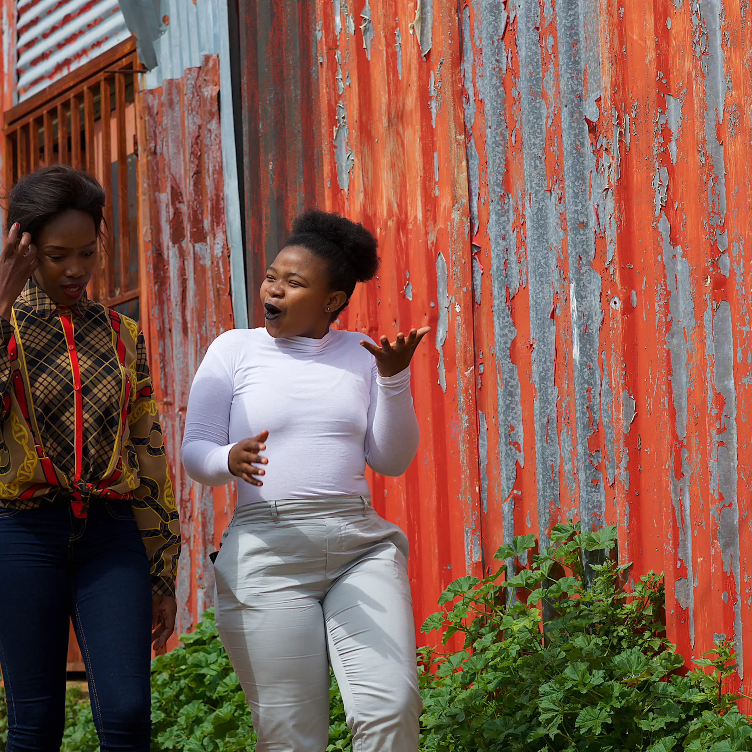 Two young women walking past a shack