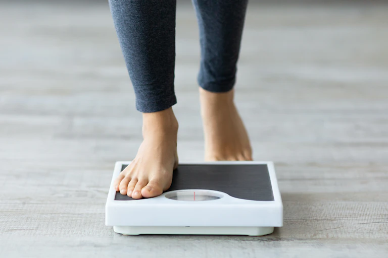 A person with bare feet steps on a scale.