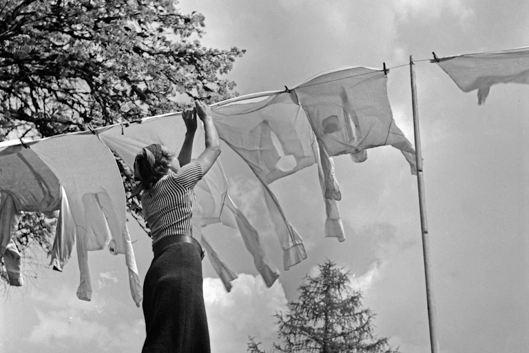 Black and white photo of a housewife hanging up fresh washing.