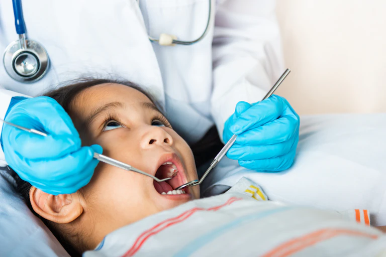 Little girl at the dentist with tools in mouth.