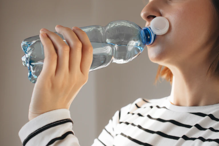 Una mujer bebiendo agua.