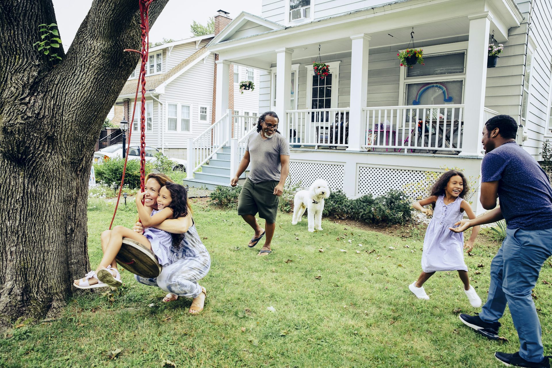 A group of people are playing outside in a front yard of a house.