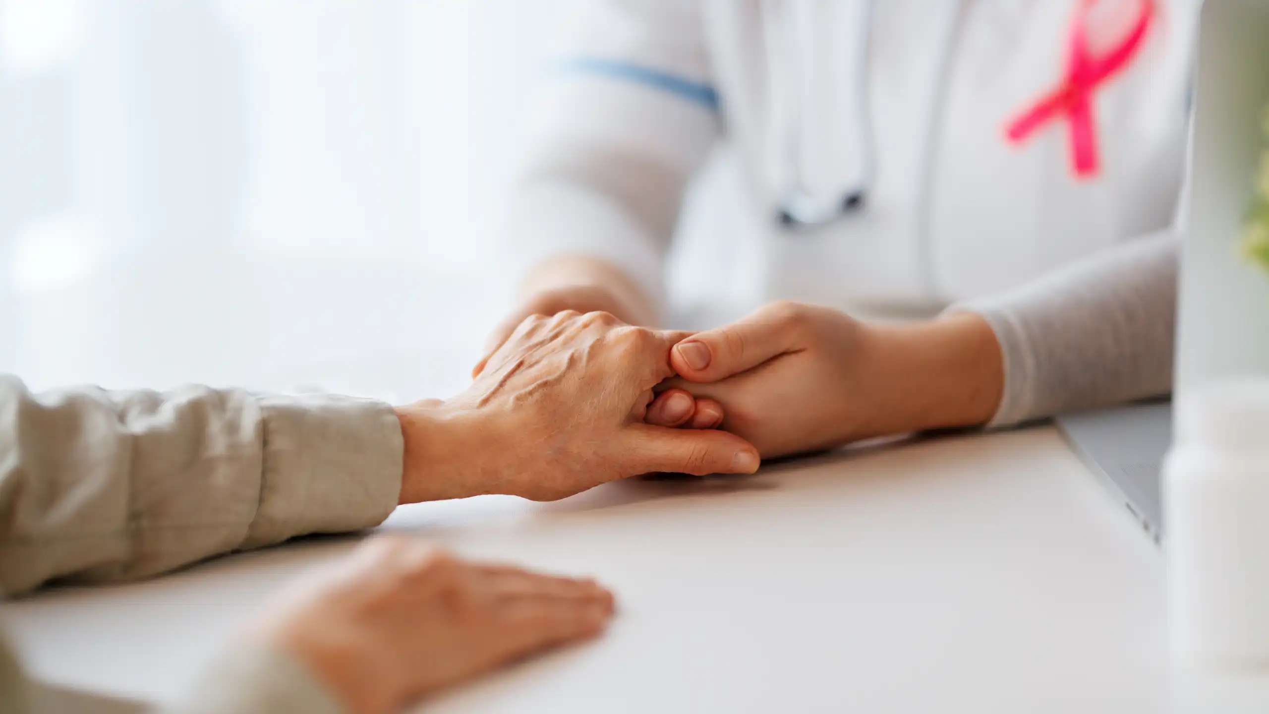 Un soignant tient la main d'un patient.