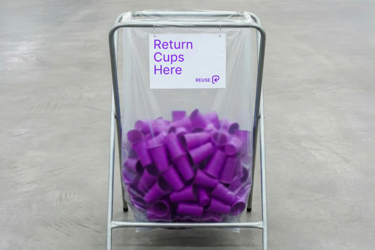 clear bin with purple cups, wording in purple says 'return cups here'