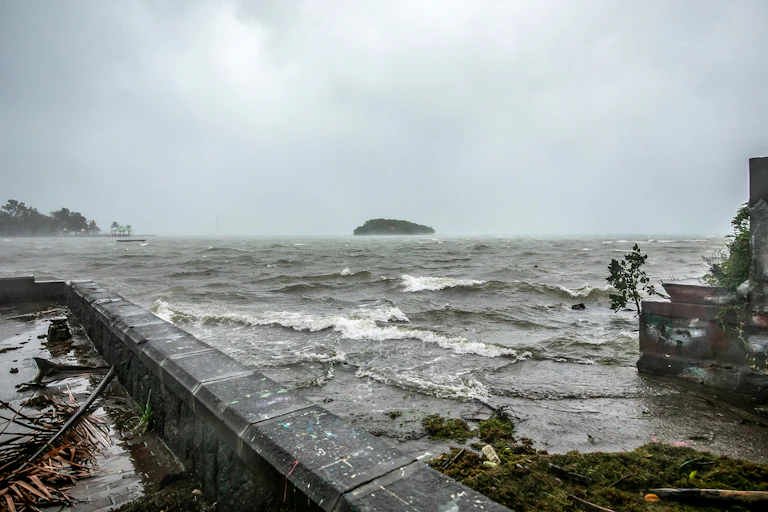 A stormy sky with waves flowing over a sea wall and windy conditions