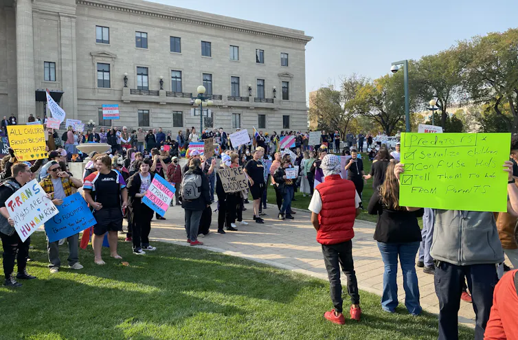 La gente sostiene pancartas frente al edificio legislativo con inscripciones.
