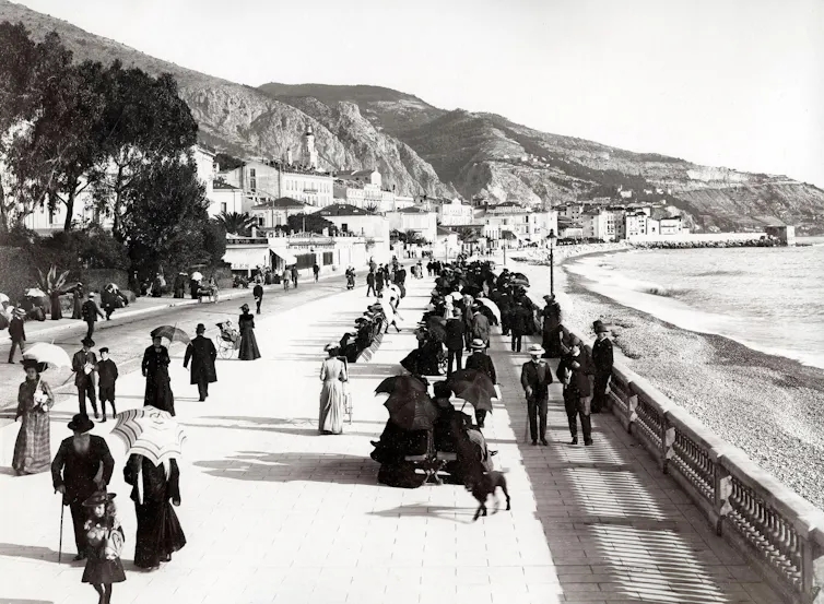 A vintage photograph of tourists strolling the promenade in Menton