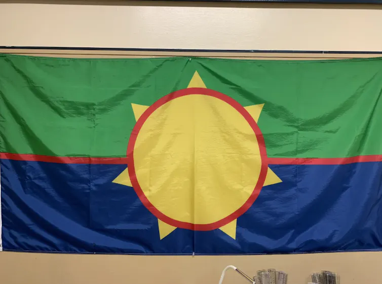 A flag with a large yellow sun in the middle with blue and green stripes.