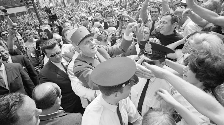 A man in cap is seen surrounded by people.