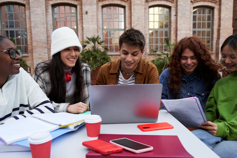 Jovens sorridentes reunidos em torno de um computador