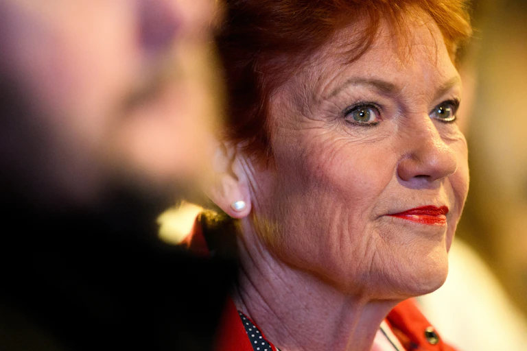 A close-up of Pauline Hanson as she looks across a room