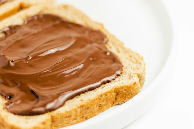 Chocolate spread on sliced bread on white plate