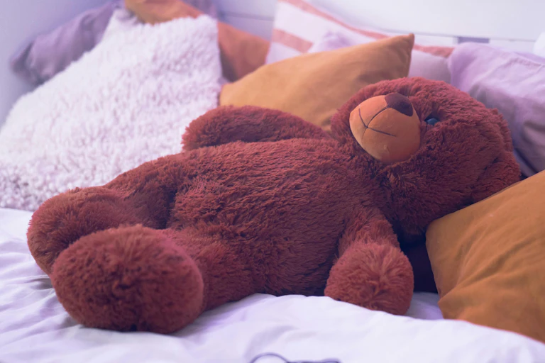 A teddy bear on a bed.