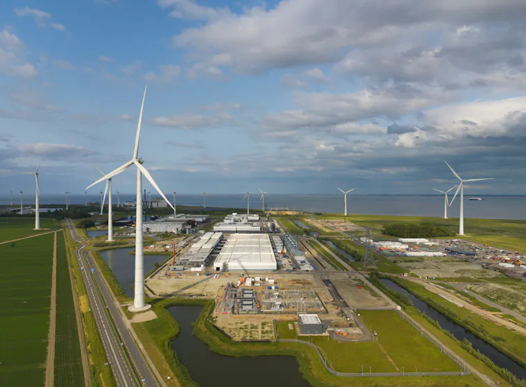 aerial view of wind turbines and a data centre warehouse set among green fields.