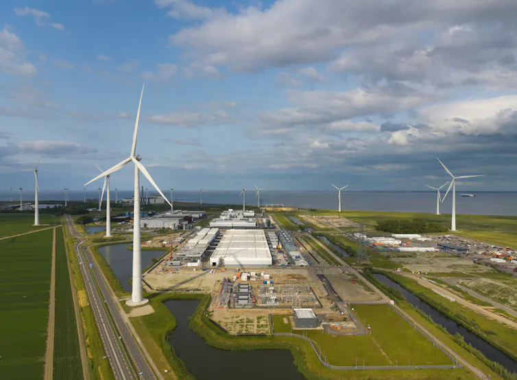 aerial view of wind turbines and a data centre warehouse set among green fields.