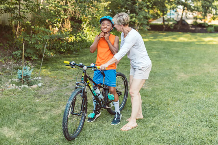 A woman helping a child ride a bike