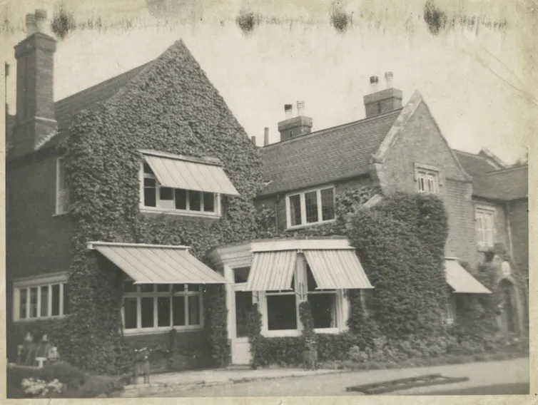 An ivy covered house with awnings over windows.