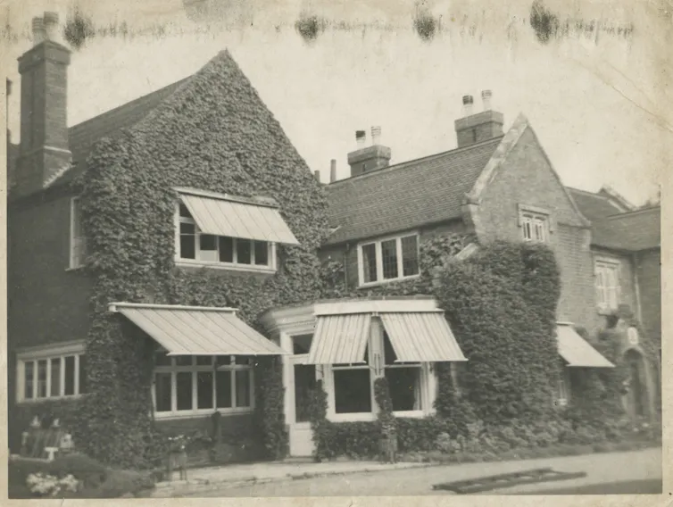 An ivy covered house with awnings over windows.