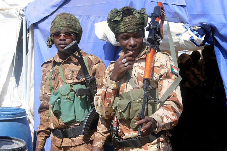 Two men wearing army fatigues and holding guns