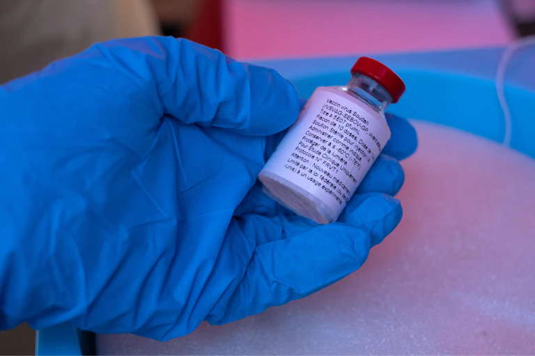 A hand holding a vial