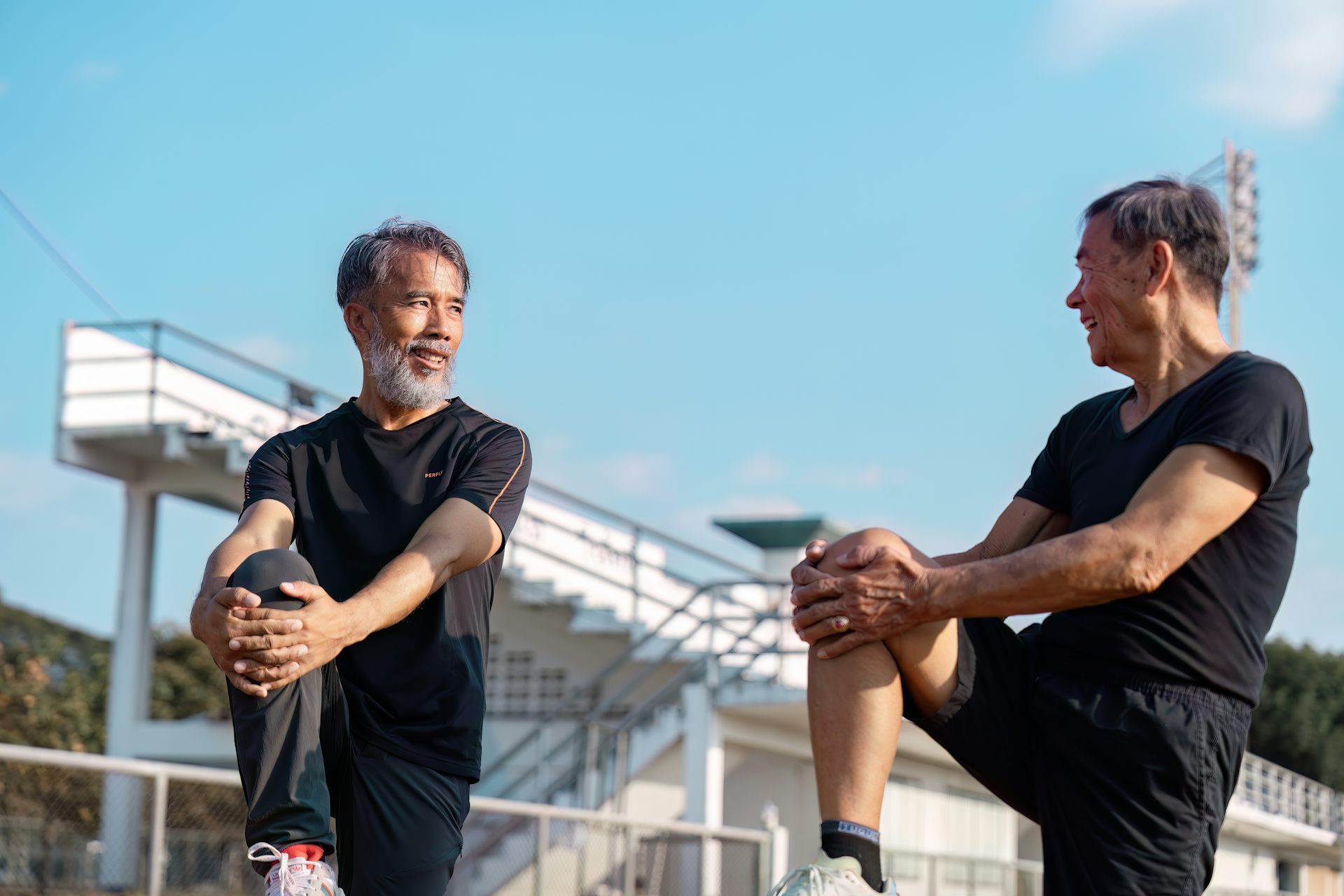 Two brothers or friends stretch their legs together before exercising.
